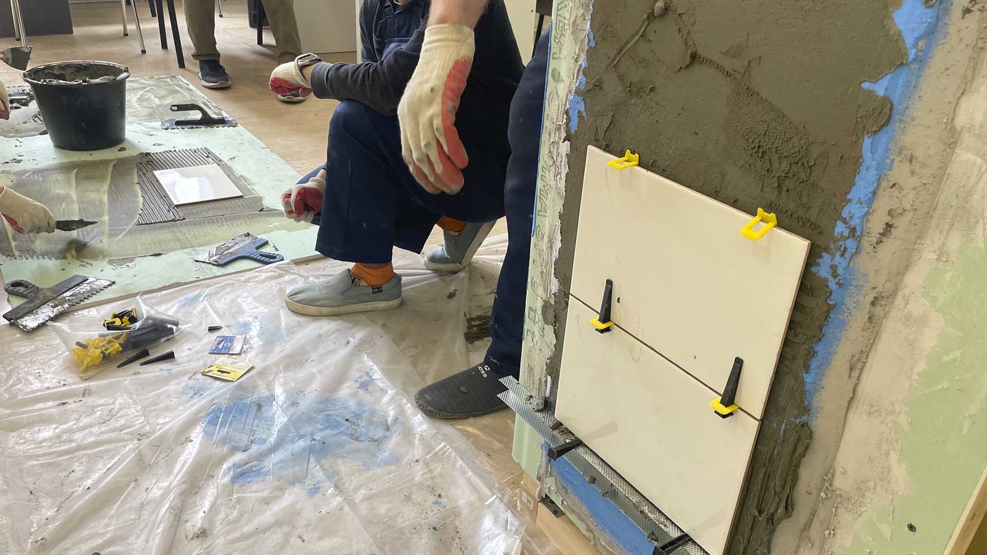 нанесение клея и укладка плитки на стенде